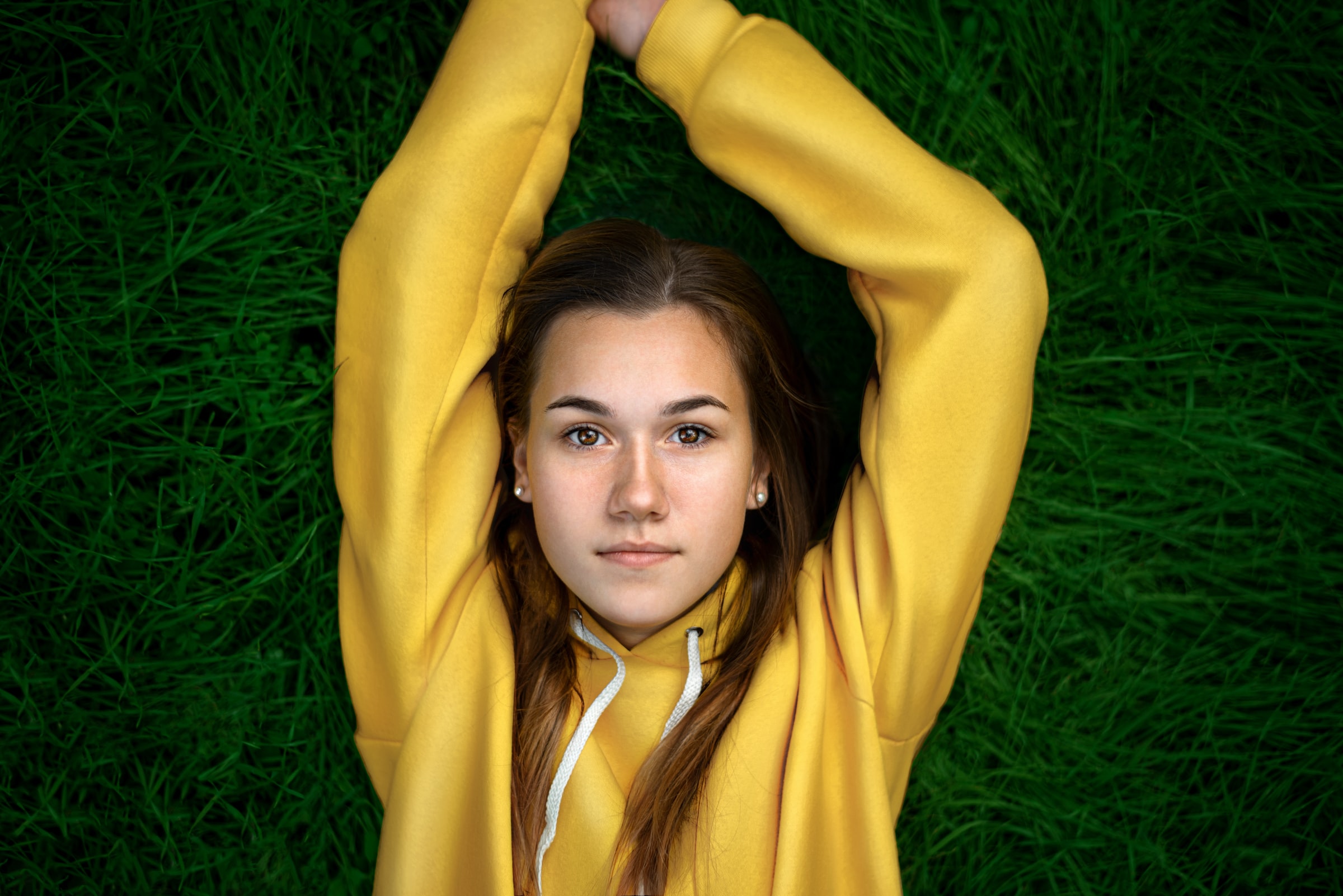 Young woman laying on the grass girl with yellow sweater and hands up lxp lifexpe